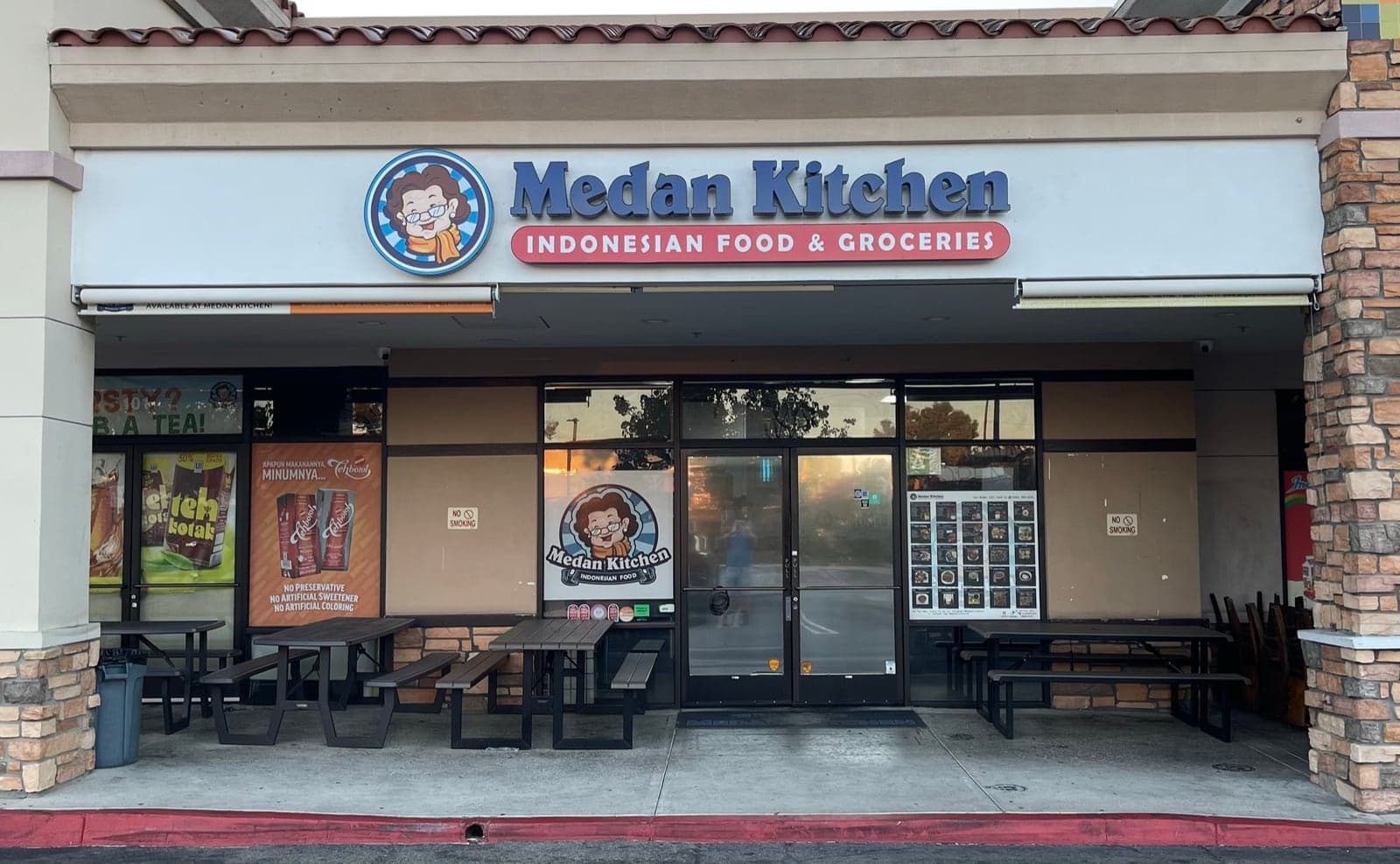 Medan Kitchen's shopfront in New Valley Plaza: a blue sign reading Medan Kitchen, Indonesian Food & Groceries, with picnic tables and the menu board beside the door